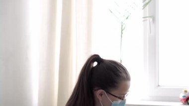 Tıp ve sağlık, pediatri, covid-19 konsepti - Kafkas Slav kökenli genç kadın hemşire ya da doktor çocuk doktorunu 8-12 aylık bebeği sarı gri kanepede muayene ediyor.