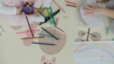 Otantik iki mutlu kardeş yaratıcı çocuklar anneleriyle birlikte kalemle çiziyorlar bahar geliyor resim gökkuşağı içeride, oyun odasında yerde eğleniyor. Çocukluk, Sanat, Eğitim, Yaratıcılık, annelik kavramı