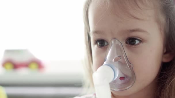 Zbliżyć kaukaski 3-4 lat nieletni dziecko przedszkola w masce inhalatora na żółtej, szarej kanapie. Dziecko biorące terapię oddechową z nebulizatorem. medycyna i zdrowie, pediatria, koncepcja covid-19 — Wideo stockowe