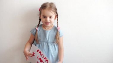 3-4 yıl boyunca beyaz çarşaf tutan beyaz saçlı, sevimli, küçük beyaz bir anaokulu kızı, aşkını ilan etti. Küçük kız, elleriyle kalp sembolü gösteren bir aşkla gülümsüyor. Romantik, Anneler Günü konsepti.