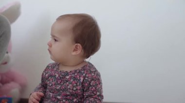 Otantik, küçük bir kız çocuğu. 1 yaşında, renkli elbiseli. Esniyor ve annesine gitmeye çalışıyor. Ebeveynlik, çocukluk, yaşam konsepti