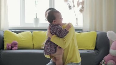 Yavaş çekim Otantik, yakın plan genç beyaz anne, küçük kız bebekle oynuyor. Evde iyi vakit geçirin. Genç kadın ağlayan çocuğu sakinleştiriyor. annelik, çocukluk, aile, yaşam tarzı kavramı