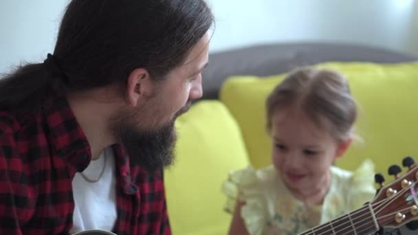 Pria bahagia dengan gaya rock menghabiskan waktu dengan balita anak bermain gitar di rumah nyaman. Ayah menyanyikan lagu-lagu untuk anak kecil yang lucu alat musik menikmati pelajaran musik domestik. keluarga, cinta, konsep hidup — Stok Video