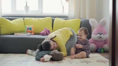 Genç neo beyaz annenin iki küçük çocukla oynadığı sahici yakın plan bebek kız ve anaokulu çocuğu evde eğleniyor. annelik, çocukluk, aile, özgünlük kavramı