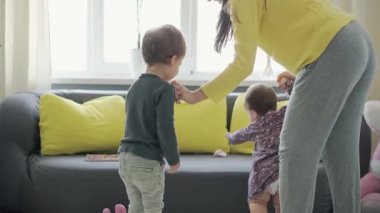 Genç neo beyaz annenin iki küçük çocukla oynadığı sahici yakın plan bebek kız ve anaokulu çocuğu evde eğleniyor. annelik, çocukluk, aile, özgünlük kavramı