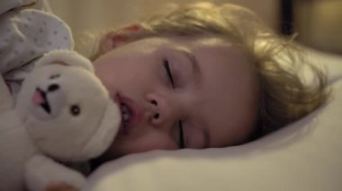 3-4 yıl boyunca tatlı beyaz bir yatakta oyuncak ayıyla tatlı tatlı tatlı uyuyan, beyaz, küçük beyaz bir anaokulu çocuğunun otantik yakın çekimi. Çocuk bakımı, Uyuyan Bebek, Çocukluk, Ebeveynlik, Yaşam Konsepti