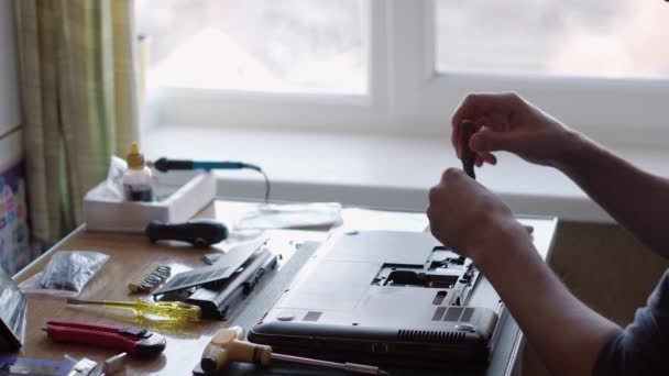 Mãos masculinas fixando laptop, aparafusar parafusos de tampa traseira com chave de fenda. serviço de reparação eletrônica. técnico que trabalha no escritório. a reparar o telefone. engenharia, avaria, conceito de tecnologia avançada — Vídeo de Stock