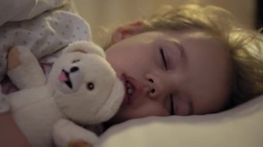 3-4 yıl boyunca tatlı beyaz bir yatakta oyuncak ayıyla tatlı tatlı tatlı uyuyan, beyaz, küçük beyaz bir anaokulu çocuğunun otantik yakın çekimi. Çocuk bakımı, Uyuyan Bebek, Çocukluk, Ebeveynlik, Yaşam Konsepti