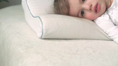 Beyaz yatakta kameraya bakan oyuncak ayıyla uyandığında küçük, şirin, beyaz bir anaokulu çocuğu uykulu bir şekilde kapanıyor. Çocuk bakımı, Uyuyan Bebek, Çocukluk, Ebeveynlik, Yaşam Konsepti