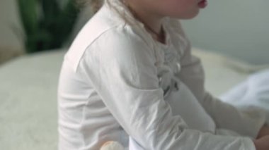 Küçük, beyaz, şirin, çocuk yaşta beyaz bir çocuğun otantik yakın çekimleri gözlerini ovuşturup beyaz yatakta esnetiyor. Çocuk bakımı, Uyuyan Bebek, Çocukluk, Ebeveynlik, Yaşam Konsepti