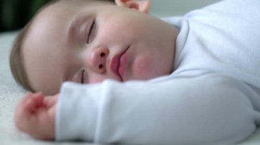 Beyaz, şirin, beyaz, tombul bir kızın otantik yakın çekimi. Mavi battaniyeyle kaplı beyaz yatakta tatlı tatlı uyur. Çocuk bakımı, Uyuyan Bebek, Çocukluk, Ebeveynlik, Yaşam Konsepti