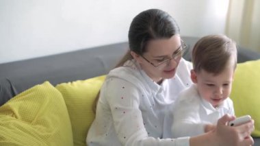 Kafkas ailesi küçük çocukları kız çocuk ve anne akıllı telefonlarıyla video konferansında evdeki oturma odasında mutluluk gülümsemesiyle sohbet ediyorlar. faaliyet teknolojisi yaşam tarzı cep telefonu kullanımı kavramı