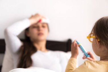 Üniforma giyen, genç anne ya da dadıyla doktorculuk oynayan, iğne yapan, ateşi ölçen, evde boş vakit geçiren, birlikte vakit geçiren, rol yapan küçük tatlı bir kız.