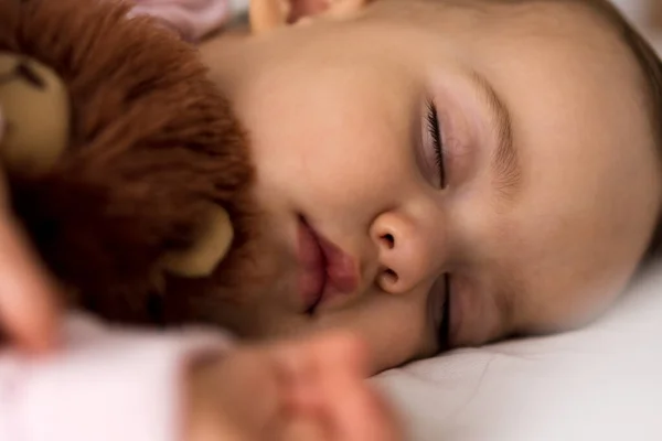 Authentiek portret schattig Kaukasisch klein baby mollig meisje of jongen in roze slaap met teddybeer op wit bed. kind rust uit rond lunchtijd. verzorging, Slaapkind, Jeugd, Ouderschap, levensloop — Stockfoto