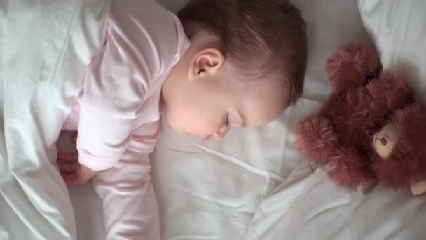 Autentico ritratto carino caucasico neonato paffuto bambina o ragazzo nel sonno rosa con orsacchiotto sul letto bianco. bambino che riposa all'ora di pranzo. cura, Bambino che dorme, Infanzia, Genitorialità, concetto di vita — Video Stock