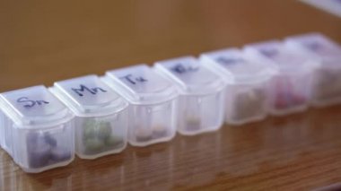 Haftanın her günü siyah kalemli haplar için plastik organizatör kutusuna yakın mesafeden yeniden odaklanıyor. Geleneksel ve Alternatif Tıp ve Sağlık, Hastalık, Salgın, covid-19 kavramı