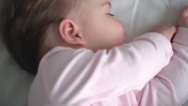 Autentický portrét roztomilý kavkazský malý baculatý holčička nebo chlapec v růžovém spánku s medvídkem na bílé posteli. dítě odpočívající v poledne. péče, Spící dítě, Dětství, Rodičovství, životní koncept — Stock video