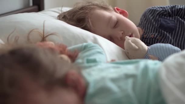 Authentic portrait cute caucasian little preschool siblings baby boy and girl in blue sleep with teddy bear on white bed. child resting at lunchtime. care, medicine and health, Childhood, life concept — Stock Video