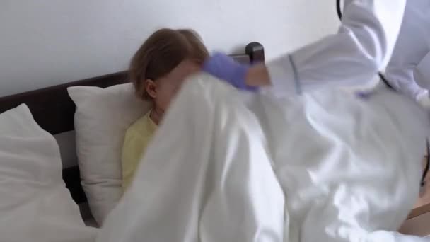 Authentique mignon caucasien mignon jeune femme infirmière ou médecin pédiatre examiner avec statoscope enfant de petite fille préscolaire mineur sur lit blanc à l'hôpital. médecine et santé, pédiatrie, concept covid-19 — Video