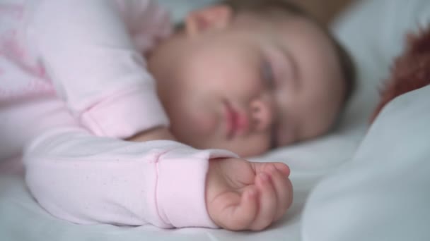 Auténtico retrato lindo bebé caucásico regordete niña o niño en sueño rosa con oso de peluche en la cama blanca. niño descansando a la hora del almuerzo. cuidado, Niñez durmiente, Infancia, paternidad, concepto de vida — Vídeo de stock