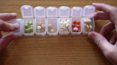 Erkek parmaklarının plastik organizatör kutusundan hap almasına çok az kaldı. İlaç planlayıcısında tedavi arayan hasta bir adam. Geleneksel ve Alternatif Tıp ve Sağlık, covid-19 kavramı