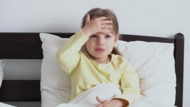 Otantik, şirin, hasta, okul öncesi çocuk sıcaklığı ölçer. Yatak odasındaki ya da hastane koğuşundaki beyaz yatakta, alnında bir avuç dolusu alyla. Tıp ve sağlık, çocukluk, covid-19 kavramı.