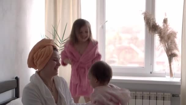 Gelukkig verenigde familie applaudisseert gezondheidswerkers, dokters en helden in de strijd tegen coronavirus pandemie. Mam en kinderen in badjassen na het bad op bed tegenover het raam. Celebration quarantaine einde concept — Stockvideo