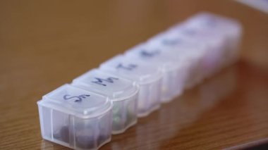 Haftanın her günü siyah kalemli haplar için plastik organizatör kutusuna yakın mesafeden yeniden odaklanıyor. Geleneksel ve Alternatif Tıp ve Sağlık, Hastalık, Salgın, covid-19 kavramı