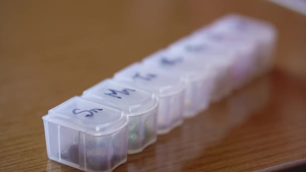 Перерозподіл з близької до віддаленої пластикової коробки для таблеток з клітинами, позначеними чорним маркером в дні тижня. Традиційна та альтернативна медицина та здоров'я, хвороби, пандемія, концепція ковідо-19 — стокове відео