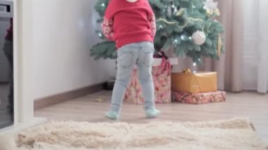 3 otantik mutlu Joy çocuğu el sallıyor ve Noel ağacı oyunuyla neşeleniyor. Birlikte iyi eğlenceler. Anaokulundaki küçük çocuklar evde yeni yılı kutluyorlar. Kış, tatil, aile kavramı