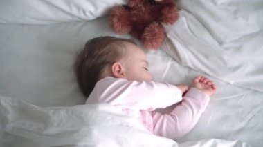 Otantik portre, beyaz yatakta oyuncak ayıyla pembe uykuda olan beyaz, beyaz, küçük, beyaz, tombul bir bebek bebek ya da oğlan. Çocuk öğle yemeği vakti dinleniyor. Bakım, Uyuyan Çocuk, Çocukluk, Ebeveynlik, Hayat Konsepti