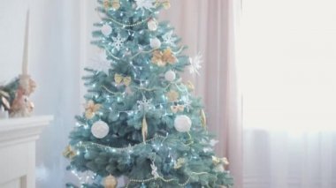 Noel Baba şapkası takan, kırmızı elbiseli, mutlu, mutlu, tombul bir kız çocuğu. Yeni yıl atmosferini kutlarken evdeki Noel ağacının yanında iyi eğlenceler. Çocukluk, bayram, kış konsepti