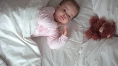 Otantik portre, beyaz yatakta oyuncak ayıyla pembe uykuda olan beyaz, beyaz, küçük, beyaz, tombul bir bebek bebek ya da oğlan. Çocuk öğle yemeği vakti dinleniyor. Bakım, Uyuyan Çocuk, Çocukluk, Ebeveynlik, Hayat Konsepti