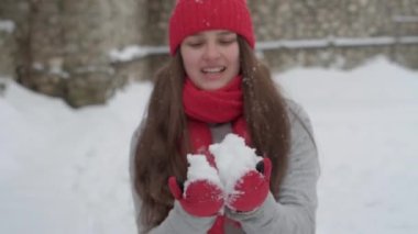 Ağır çekimde, otantik, mutlu, uzun, dalgalı saçlı, kırmızı şapkalı, eşarplı, kameraya bakan kar tanelerinin üstüne kar püskürten güzel bir kadın. Annelik, Anneler Günü konsepti