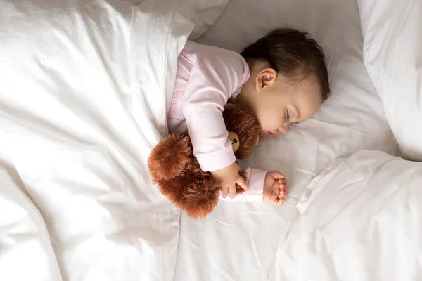 Authentiek portret schattig Kaukasisch klein baby mollig meisje of jongen in roze slaap met teddybeer op wit bed. kind rust uit rond lunchtijd. verzorging, Slaapkind, Jeugd, Ouderschap, levensloop — Stockfoto