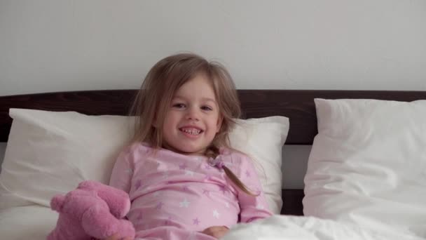 Autentyczne kaukaskie 2 małe rodzeństwo przedszkolak dziewczynka chłopiec w różowy niebieski senny po przebudzeniu patrząc na aparat uśmiechnięty słodkie i grymasy w białym łóżku. Opieka nad dziećmi, Dzieciństwo, Rodzicielstwo, koncepcja życia — Wideo stockowe