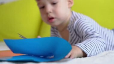 Çevrimiçi öğrenim sanatı eğitimi - Yaratıcı bir okul çocuğu makas makasıyla renkli kağıt keserek resim yapıyor. Küçük bebek mutlu çocuk evde karantinada, el hareketliliği