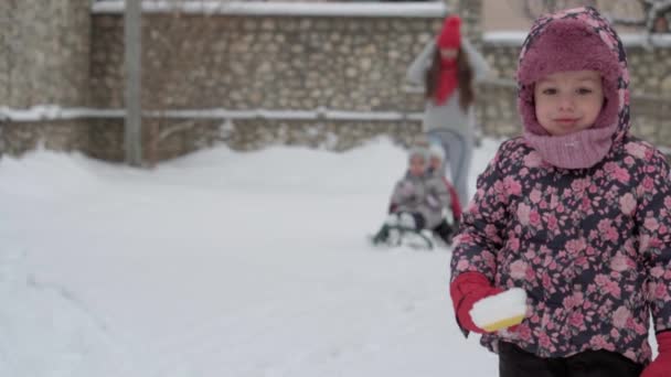 Zima, wakacje, gra, koncepcja rodziny - ogólny plan autentyczne małe przedszkole moll 3-4 lat dziewczyna w fioletowym na pokryte śniegiem łąki stoisk poczętych i patrzy w obiektyw. dzieciak na zaśnieżonym terenie. — Wideo stockowe