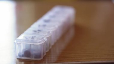 Haftanın her günü siyah kalemli haplar için plastik organizatör kutusuna yakın mesafeden yeniden odaklanıyor. Geleneksel ve Alternatif Tıp ve Sağlık, Hastalık, Salgın, covid-19 kavramı