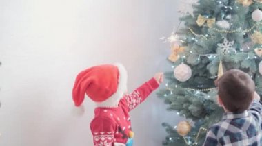Süslü Noel ağacının yanında maytaplı neşeli çocuklar birlikte iyi eğlenceler. Anaokulundaki küçük bebek evde yeni yılı kutluyor. Kış, tatil, aile kavramı