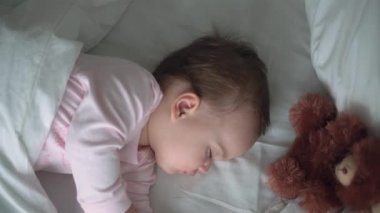 Otantik portre, beyaz yatakta oyuncak ayıyla pembe uykuda olan beyaz, beyaz, küçük, beyaz, tombul bir bebek bebek ya da oğlan. Çocuk öğle yemeği vakti dinleniyor. Bakım, Uyuyan Çocuk, Çocukluk, Ebeveynlik, Hayat Konsepti