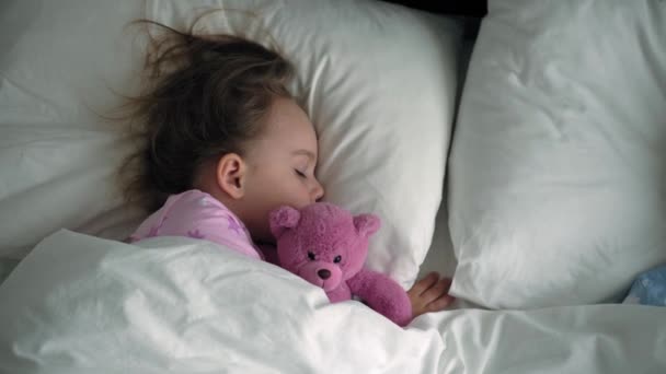 Top view autentické roztomilé kavkazské malé předškolní sourozenci chlapeček a dívka v modré růžové pyžamo spát s plyšovým medvídkem na bílé posteli. dětský odpočinek, péče, medicína a zdraví, Dětství, životní koncept — Stock video