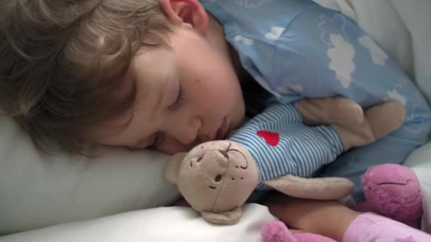 Top view αυθεντικό χαριτωμένο καυκάσιος λίγο προνήπιο αδέλφια αγοράκι και κορίτσι σε μπλε ροζ πιτζάμες ύπνο με αρκουδάκι σε λευκό κρεβάτι. παιδική ανάπαυση, φροντίδα, ιατρική και υγεία, παιδική ηλικία, έννοια της ζωής — Αρχείο Βίντεο