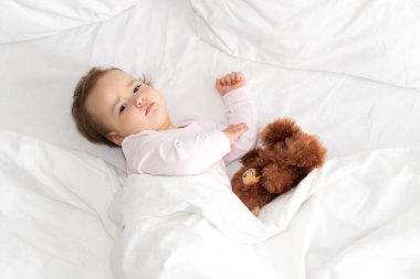 Otantik portre şirin beyaz beyaz bebek tombul kız ya da beyaz yatakta kameraya bakan oyuncak ayıyla uyandığında pembe uykulu oğlan. Çocuk bakımı, Çocukluk, Ebeveynlik, yaşam tarzı konsepti