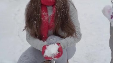 Ağır çekimde, otantik, mutlu, uzun, dalgalı saçlı, kırmızı şapkalı, eşarplı, kameraya bakan, güzel gülümsemeli, elleri başının üstünde kar kusan güzel bir kadın. Annelik, Anneler Günü konsepti