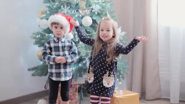 3 niños felices auténticos alegría saludar de la mano regocijarse por el juego del árbol de Navidad divertirse juntos. Los niños preescolares celebran el ambiente festivo de Año Nuevo en casa. Invierno, vacaciones, concepto familiar — Vídeos de Stock