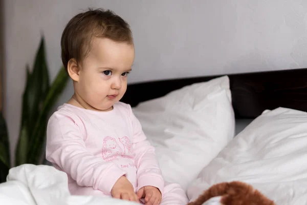 真人肖像可爱的高加索小宝宝胖胖的女婴或粉红困倦的男婴醒来时，在白色的床上看着相机。儿童保育、童年、父母、生活方式概念 — 图库照片