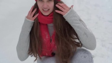 Ağır çekimde, otantik, mutlu, uzun, dalgalı saçlı, kırmızı şapkalı, eşarplı, kameraya bakan kar tanelerinin üstüne kar püskürten güzel bir kadın. Annelik, Anneler Günü konsepti