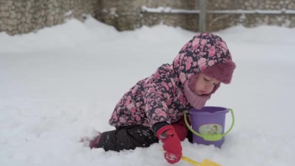 Winter, vacation, games, family concepts - middle plan of authentic little preschool minor 3-4 years old girl in purple on snow-covered meadow plays with snow in countryside. child runs on snowy area — Stock Video