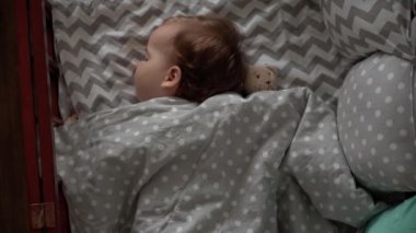 Otantik şirin, tombul bir kız çocuğu ya da erkek çocuk öğle yemeği vakti yatak odasında oyuncak ayıyla tatlı tatlı uyur. Çocuk gri yatakta yatıyor. Çocukluk, ebeveynlik, tıp, sağlık konsepti